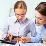 Two accountants performing detailed data entry bookkeeping.