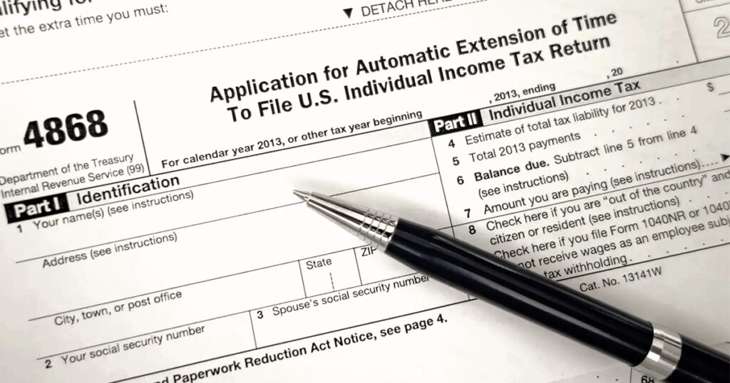 Tax extension form with pen placed on paperwork.