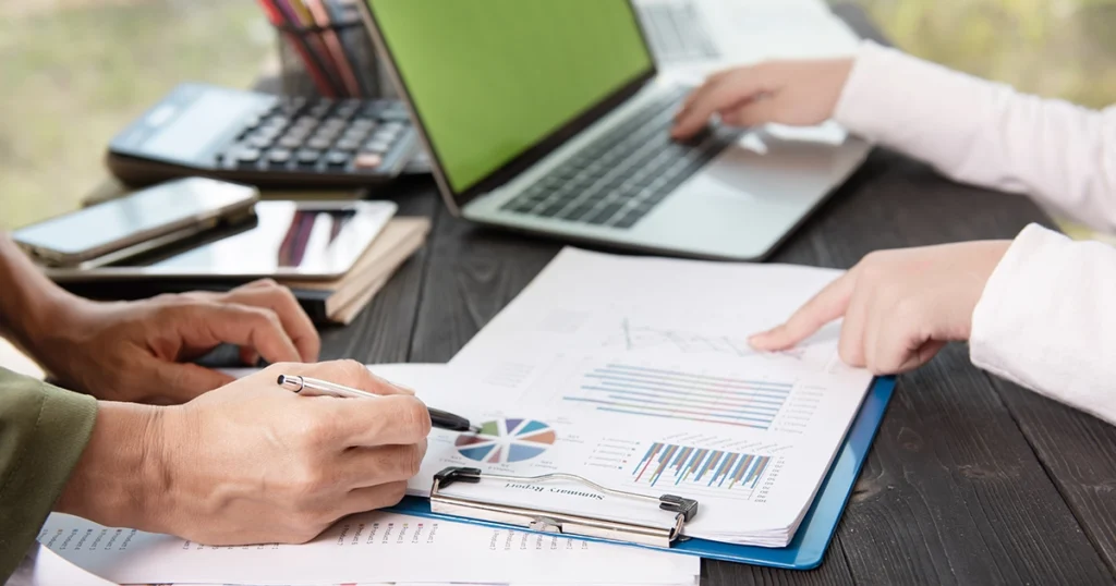 Two professionals reviewing financial charts on a clipboard