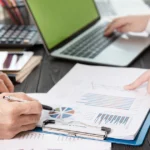 Two professionals reviewing financial charts on a clipboard