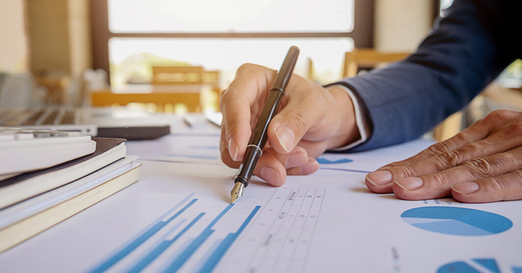 Professional analyzing financial charts and data with a fountain pen.