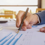 Professional analyzing financial charts and data with a fountain pen.
