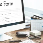 Computer monitor displaying digital tax form in wooden office.