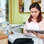 Female store clerk using a digital tablet at a cash register.